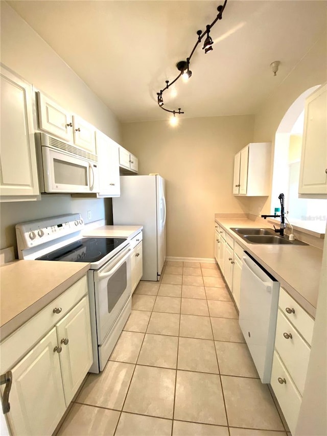 kitchen with track lighting, a sink, light tile patterned flooring, white appliances, and light countertops