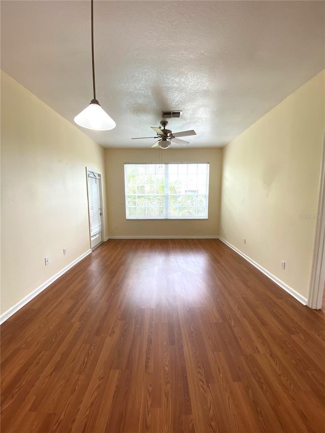 spare room featuring a ceiling fan, baseboards, a textured ceiling, and dark wood finished floors