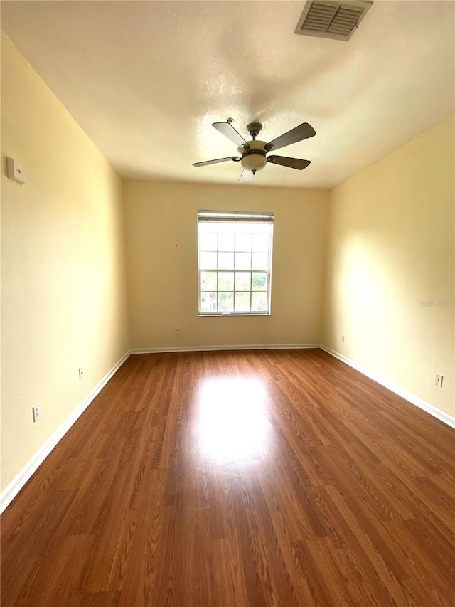 empty room with baseboards, wood finished floors, visible vents, and ceiling fan