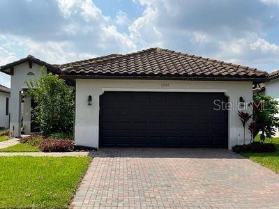 5060 Arancia Ln, Ave Maria, FL 34142 - mediterranean / spanish-style house with decorative driveway, stucco siding, a tiled roof, and a garage