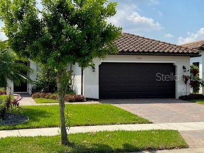 5060 Arancia Ln, Ave Maria, FL 34142 - view of front facade featuring driveway, a tile roof, a front yard, stucco siding, and a garage