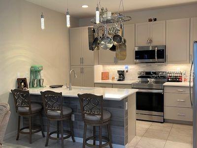 5060 Arancia Ln, Ave Maria, FL 34142 - kitchen with a breakfast bar area, tasteful backsplash, appliances with stainless steel finishes, and light countertops