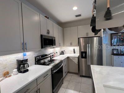 5060 Arancia Ln, Ave Maria, FL 34142 - kitchen with appliances with stainless steel finishes, light tile patterned flooring, light countertops, and backsplash