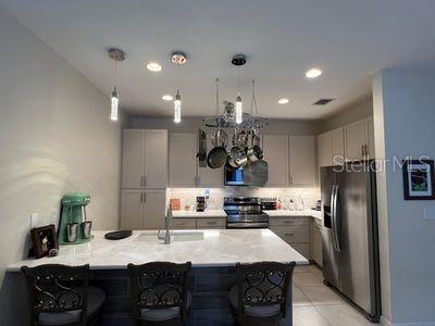 5060 Arancia Ln, Ave Maria, FL 34142 - kitchen featuring a kitchen breakfast bar, backsplash, stainless steel appliances, a peninsula, and gray cabinets