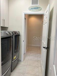 5060 Arancia Ln, Ave Maria, FL 34142 - laundry area featuring light tile patterned floors, visible vents, baseboards, washer and clothes dryer, and cabinet space