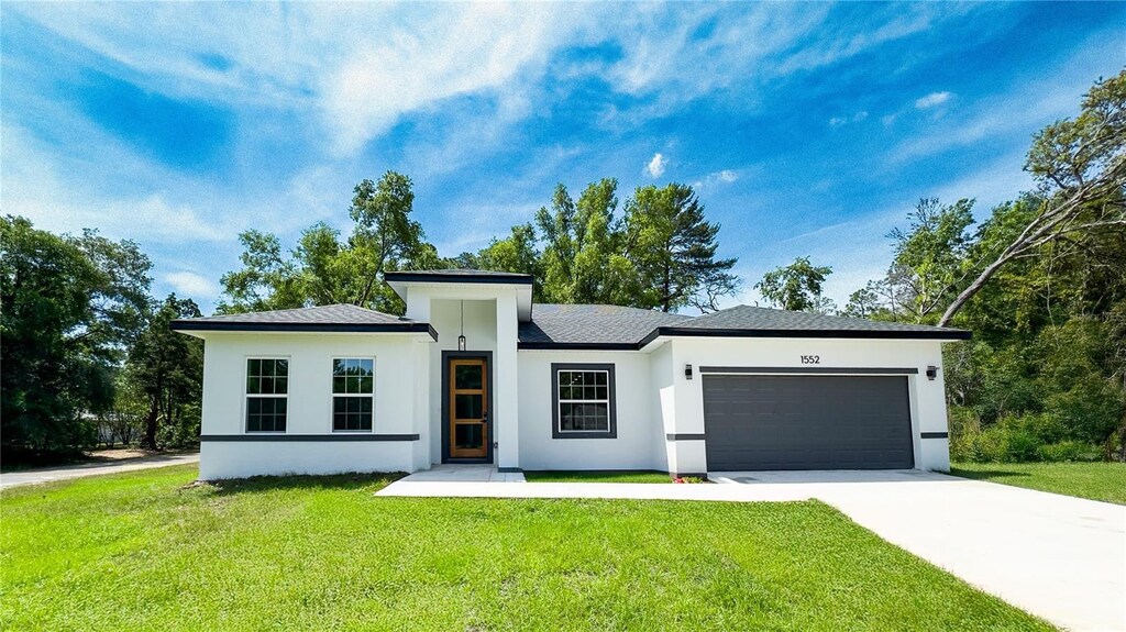 1552 W Lavender Ln, Citrus Springs, FL 34434 - prairie-style home with a garage, driveway, a front lawn, and stucco siding
