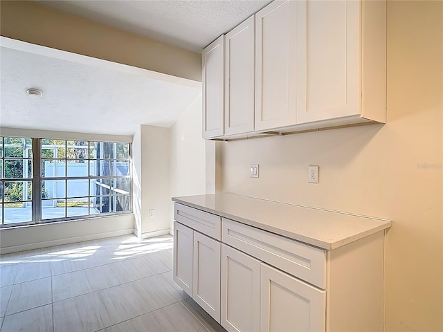 21940 Dupree Dr, Land O Lakes, FL 34639 - kitchen with white cabinets, light countertops, a textured ceiling, baseboards, and lofted ceiling