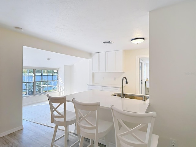 21940 Dupree Dr, Land O Lakes, FL 34639 - kitchen featuring visible vents, a breakfast bar area, light countertops, white cabinetry, and a sink