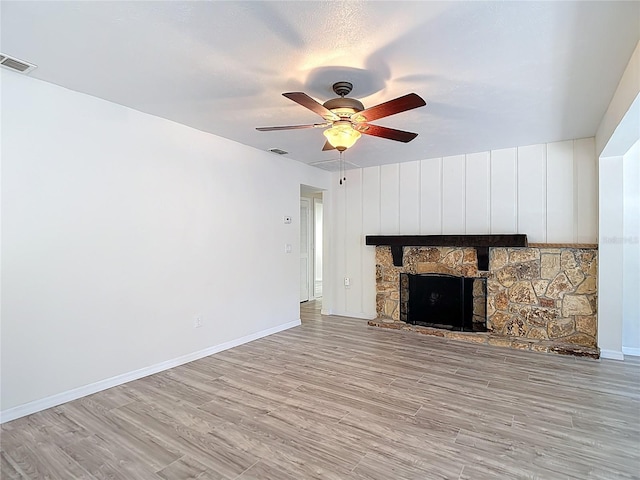 21940 Dupree Dr, Land O Lakes, FL 34639 - unfurnished living room featuring ceiling fan, a stone fireplace, visible vents, baseboards, and light wood-style flooring