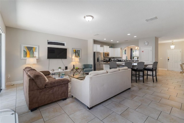 4201 Oakview Dr, Davenport, FL 33837 - living room with arched walkways, baseboards, visible vents, and light tile patterned floors