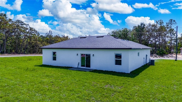 6257 SW 153 Rd Ln, Ocala, FL 34473 - back of property featuring a lawn, central AC unit, stucco siding, and roof with shingles
