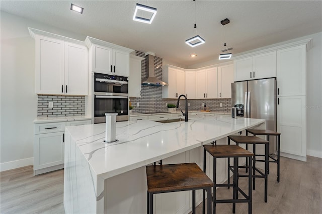 59 W 10th St, Apopka, FL 32703 - kitchen featuring stainless steel appliances, wall chimney range hood, light wood-style floors, white cabinets, and recessed lighting