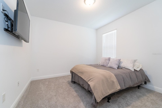 bedroom with light colored carpet and baseboards