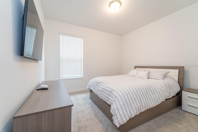 bedroom with light colored carpet and baseboards