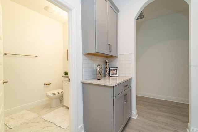 bar with decorative backsplash, arched walkways, and baseboards