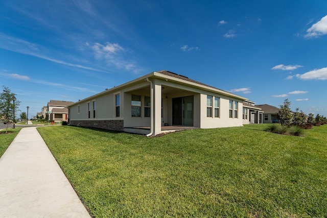 back of property with stucco siding and a lawn
