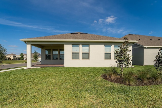 back of property with stucco siding, a patio area, and a lawn