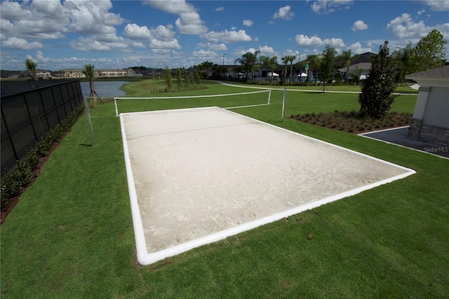 view of property's community featuring volleyball court, a lawn, fence, and a water view