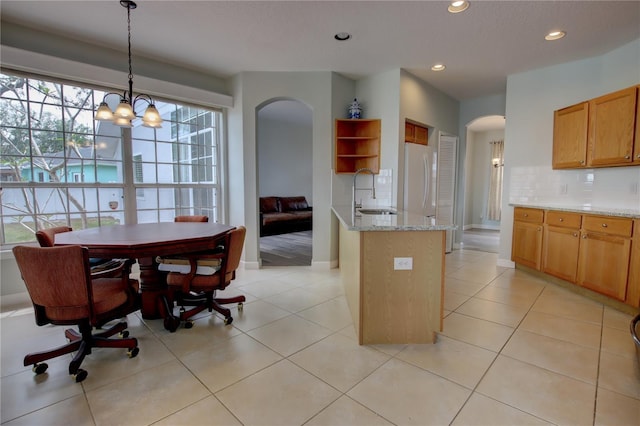 kitchen featuring arched walkways, recessed lighting, decorative backsplash, and a sink