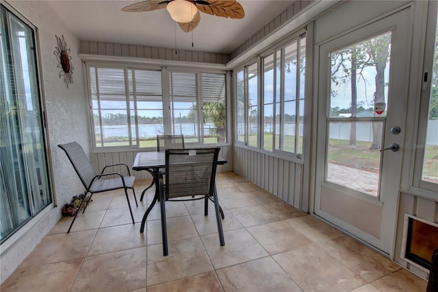 sunroom with plenty of natural light, a water view, and tile patterned floors