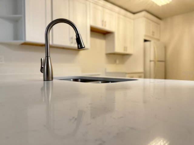 604 Kenwick Cir Unit 105, Casselberry, FL 32707 - interior details with a sink, freestanding refrigerator, white cabinetry, light stone counters, and open shelves