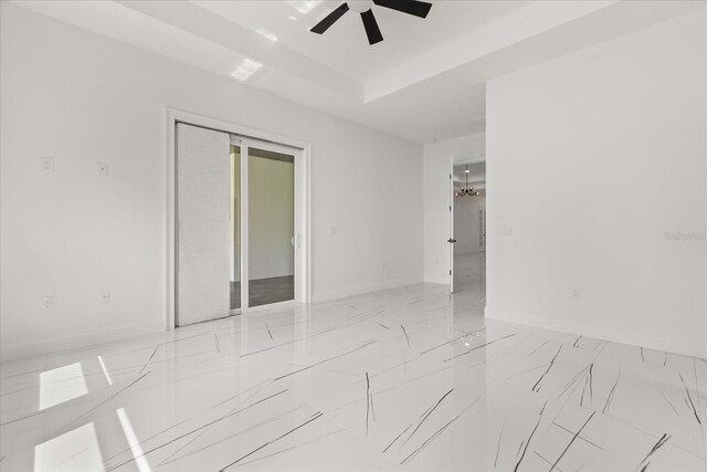 16500 Magnolia Terrace Blvd, Montverde, FL 34756 - unfurnished room with light marble finish flooring, ceiling fan, baseboards, and a raised ceiling