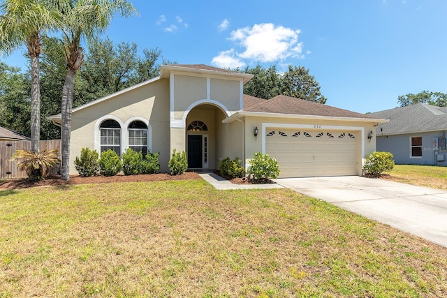 mediterranean / spanish-style house featuring fence, a front lawn, a garage, stucco siding, and concrete driveway