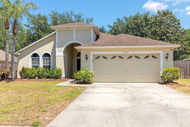 view of front of house featuring fence, a front lawn, a garage, stucco siding, and driveway