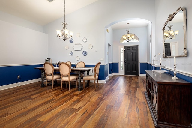 entryway featuring arched walkways, high vaulted ceiling, a chandelier, and dark wood-type flooring