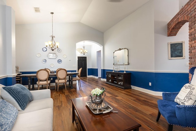 living room with visible vents, wood finished floors, high vaulted ceiling, a chandelier, and arched walkways