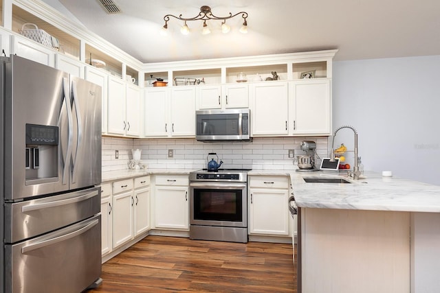 kitchen with appliances with stainless steel finishes, a sink, dark wood finished floors, a peninsula, and visible vents