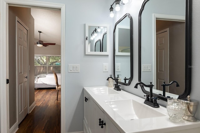 full bathroom featuring ceiling fan, vaulted ceiling, a sink, and wood finished floors