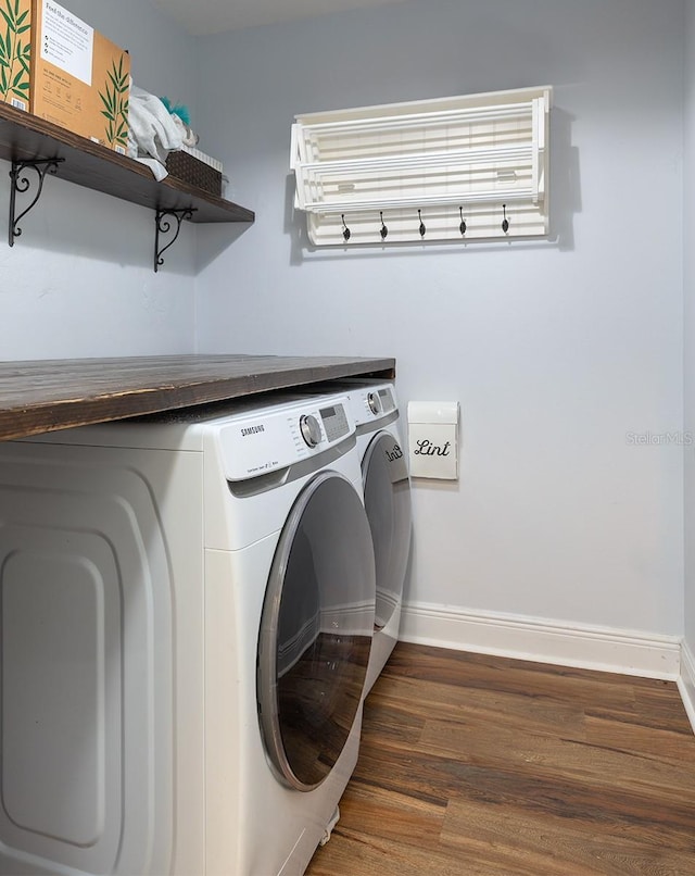 clothes washing area with laundry area, washer and clothes dryer, baseboards, and wood finished floors