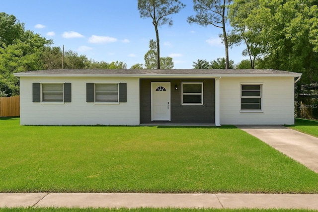 ranch-style house with fence, covered porch, a shingled roof, and a front lawn