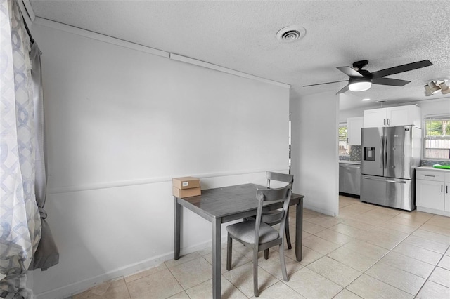 dining room with a textured ceiling, visible vents, a ceiling fan, and light tile patterned floors
