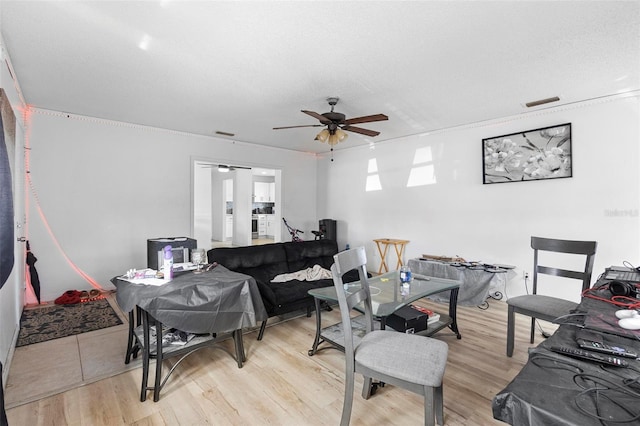 living room with ceiling fan, visible vents, and light wood finished floors