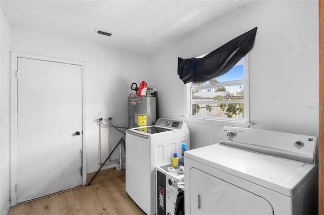 washroom with washer and clothes dryer, light wood-style floors, water heater, laundry area, and visible vents