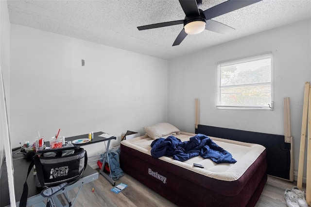 bedroom with wood finished floors, a textured ceiling, and ceiling fan