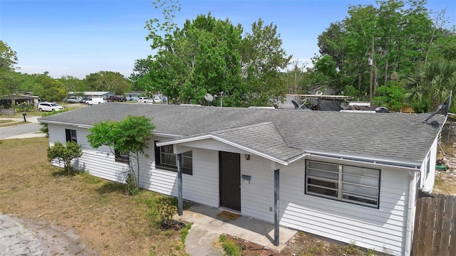 ranch-style home featuring a shingled roof and fence