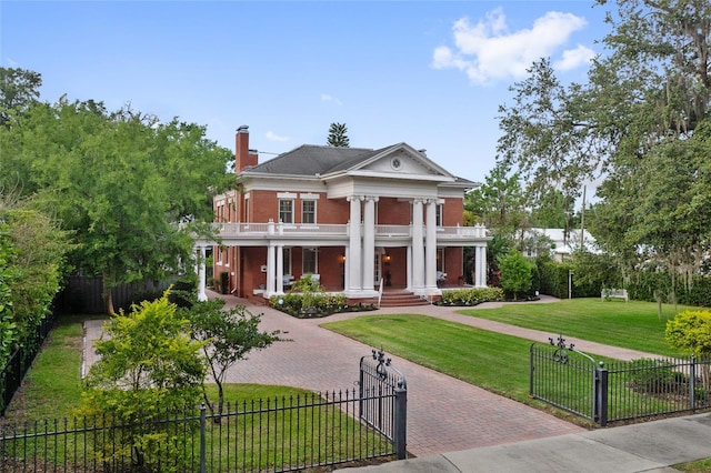 greek revival inspired property featuring a porch, a gate, a balcony, a fenced front yard, and decorative driveway
