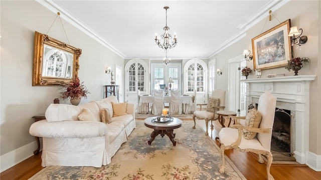living area with baseboards, a chandelier, crown molding, wood finished floors, and a fireplace