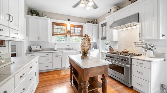 kitchen with white cabinetry, light countertops, high end stainless steel range, and wall chimney exhaust hood