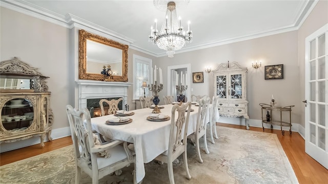dining area featuring an inviting chandelier, ornamental molding, a high end fireplace, and wood finished floors