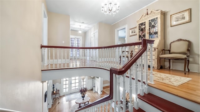 staircase featuring an inviting chandelier, plenty of natural light, wood finished floors, and arched walkways