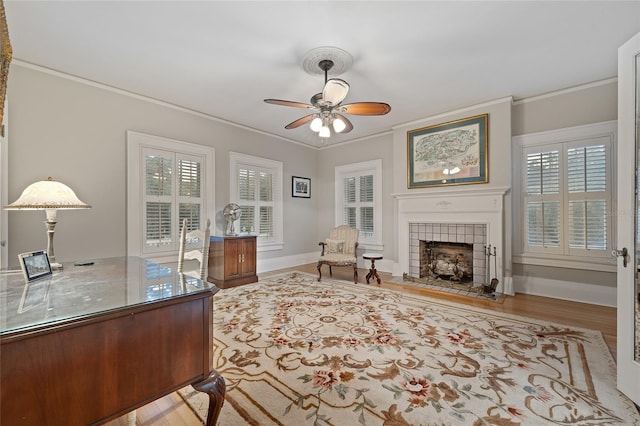 home office with a fireplace, crown molding, a wealth of natural light, and a ceiling fan