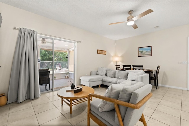 living area with light tile patterned floors, ceiling fan, baseboards, and a textured ceiling