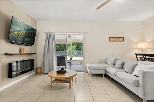living room featuring light tile patterned floors, ceiling fan, and a glass covered fireplace