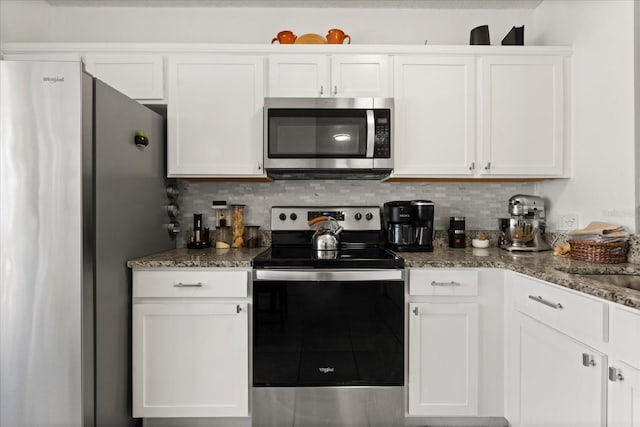 kitchen featuring white cabinetry, dark stone countertops, appliances with stainless steel finishes, and decorative backsplash