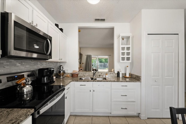 kitchen with light tile patterned flooring, stainless steel microwave, electric stove, and a sink