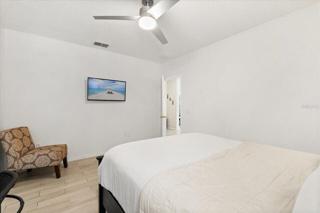 bedroom with visible vents, a ceiling fan, light wood-style flooring, and baseboards